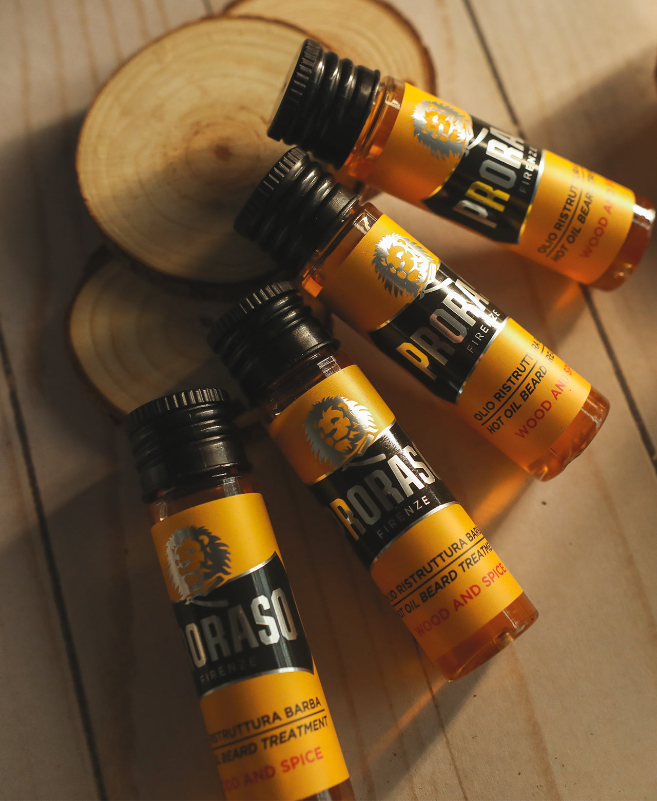 Four Hot Oil Beard Treatment Vials laying on top of Cedar Wood slices on a blonde wood background 