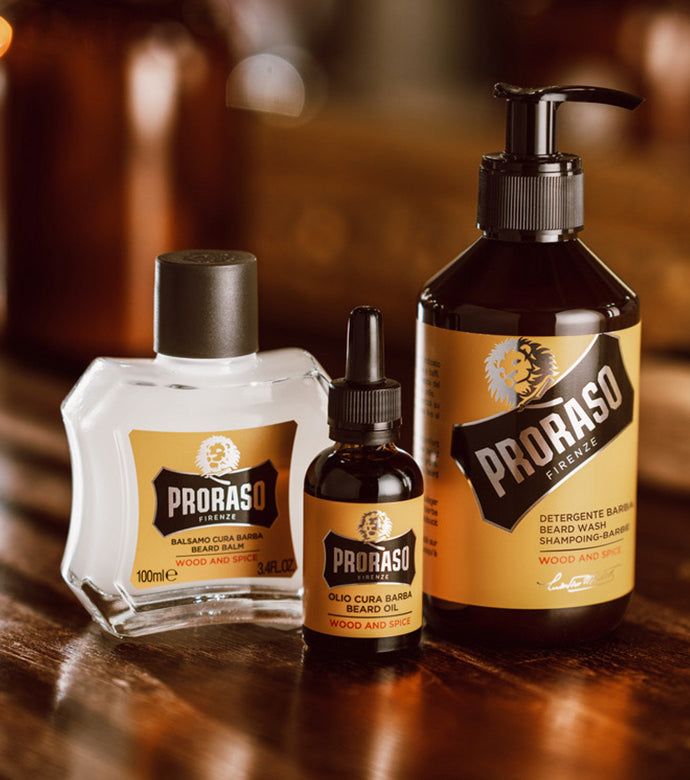Wood & Spice Beard lineup from left to right: Beard Balm, Beard Oil and Beard Wash sitting on wooden barbershop shelf.